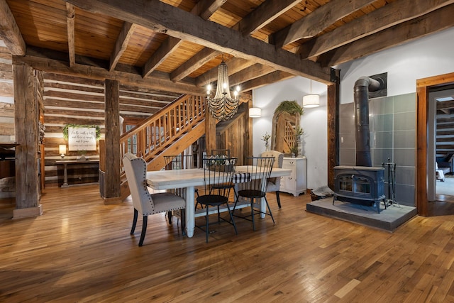 dining area featuring a wood stove, wood ceiling, beam ceiling, wood-type flooring, and a chandelier