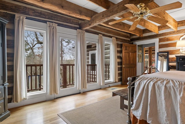 bedroom featuring beam ceiling, light hardwood / wood-style floors, and access to outside