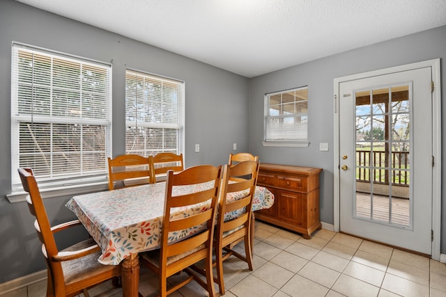 dining room with light tile patterned floors, baseboards, and a textured ceiling