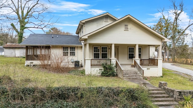 view of front facade featuring a front lawn, central air condition unit, and covered porch