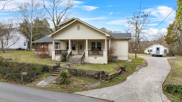 bungalow-style home featuring stairway, covered porch, concrete driveway, and a front lawn