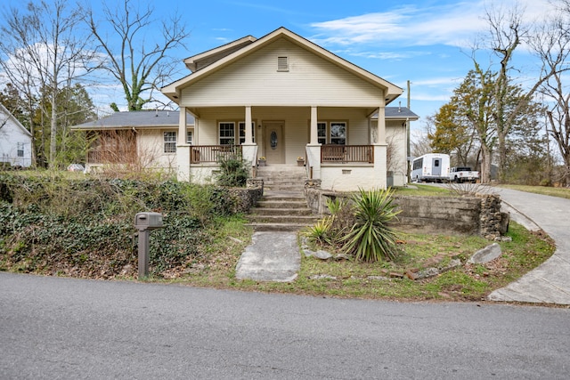 bungalow featuring stairway, a porch, and driveway