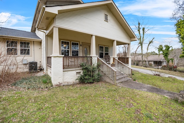 view of front of property with covered porch, a front yard, and central AC