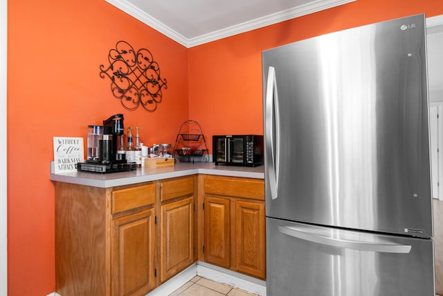 kitchen featuring crown molding, light tile patterned floors, light countertops, and freestanding refrigerator