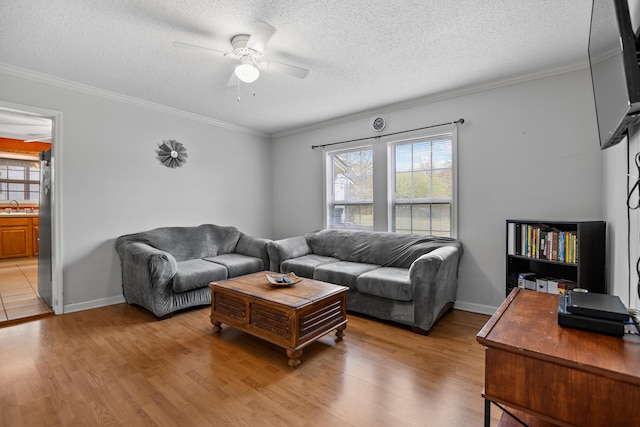 living room featuring light wood-style flooring, a textured ceiling, ceiling fan, and ornamental molding