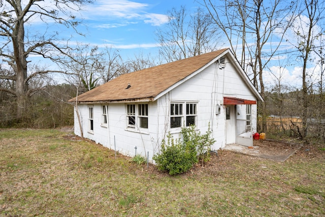 view of side of property with a lawn and a shingled roof