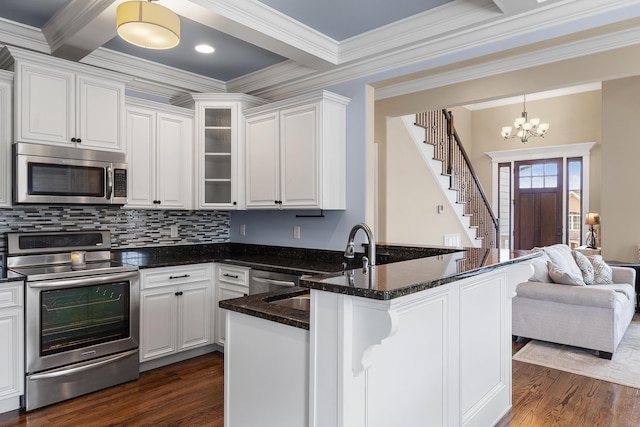 kitchen featuring appliances with stainless steel finishes, dark stone countertops, white cabinets, dark hardwood / wood-style flooring, and kitchen peninsula
