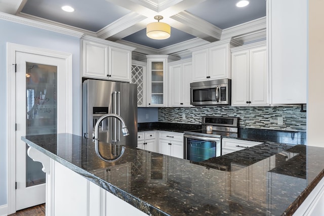 kitchen with beamed ceiling, white cabinetry, dark stone countertops, backsplash, and stainless steel appliances