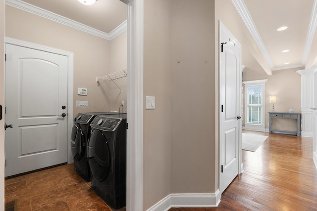 laundry area with decorative columns, crown molding, washer and dryer, and dark wood-type flooring