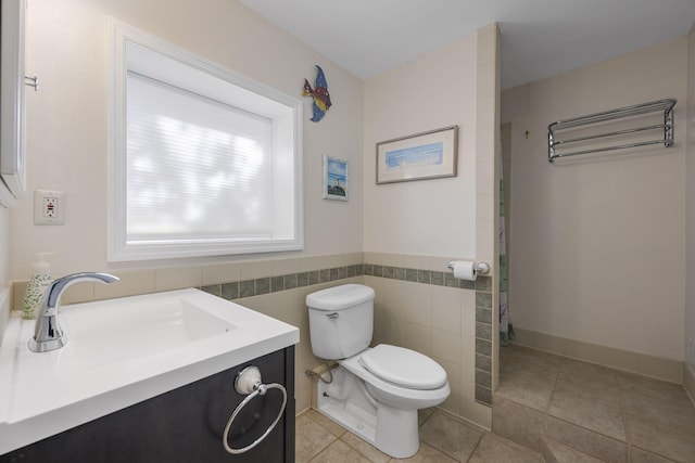 bathroom featuring vanity, toilet, tile patterned flooring, and tile walls