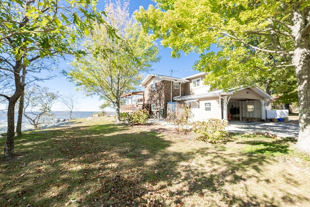 view of yard with a deck with water view and a carport