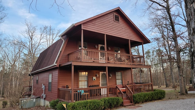 rustic home with a porch, roof with shingles, and a gambrel roof