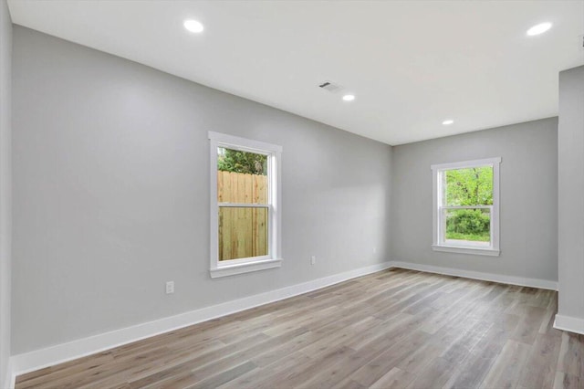 unfurnished room with baseboards, wood finished floors, visible vents, and recessed lighting