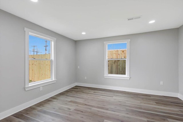 unfurnished room with baseboards, wood finished floors, visible vents, and recessed lighting