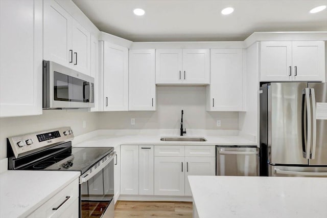 kitchen with light countertops, a sink, white cabinetry, and appliances with stainless steel finishes