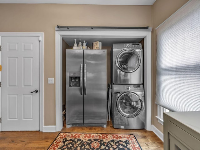 laundry room with stacked washer and dryer and light hardwood / wood-style floors