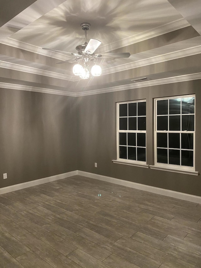 empty room featuring a tray ceiling, ornamental molding, dark hardwood / wood-style floors, and ceiling fan