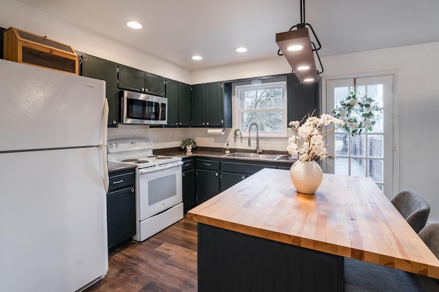 kitchen with dark hardwood / wood-style floors, pendant lighting, wood counters, sink, and white appliances