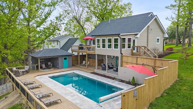 back of property with a fenced in pool, a shingled roof, a patio area, a fenced backyard, and an outdoor structure