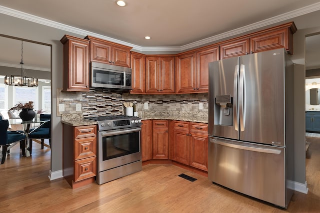 kitchen featuring brown cabinetry, appliances with stainless steel finishes, light stone counters, ornamental molding, and backsplash