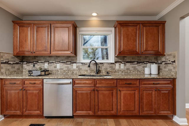 kitchen with light wood-style flooring, light stone counters, ornamental molding, stainless steel dishwasher, and a sink