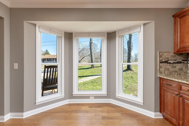 interior space with plenty of natural light, crown molding, light wood-type flooring, and baseboards