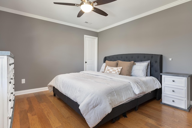 bedroom featuring baseboards, crown molding, visible vents, and wood finished floors