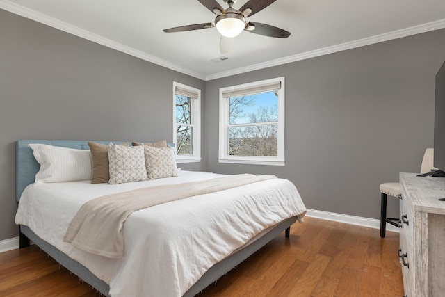 bedroom featuring visible vents, crown molding, baseboards, and wood finished floors