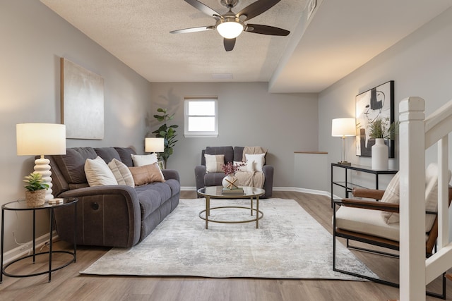 living room featuring baseboards, a textured ceiling, visible vents, and wood finished floors