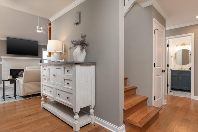 stairway with a fireplace, crown molding, and wood finished floors