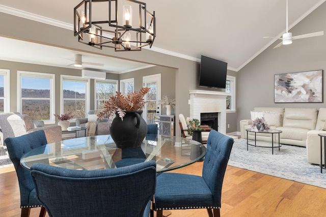 dining room featuring ornamental molding, ceiling fan with notable chandelier, a brick fireplace, and wood finished floors