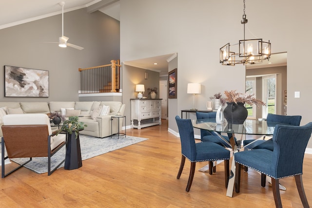 dining area with high vaulted ceiling, light wood-style floors, ornamental molding, a chandelier, and baseboards