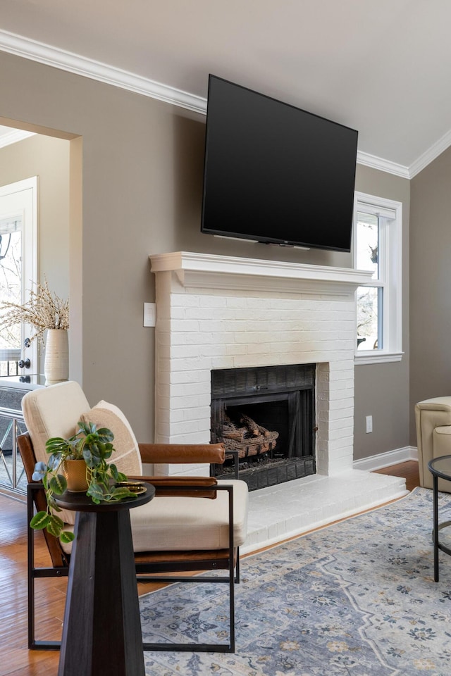 living room with a fireplace, crown molding, baseboards, and wood finished floors