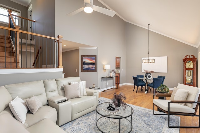 living area featuring crown molding, stairway, wood finished floors, high vaulted ceiling, and ceiling fan with notable chandelier