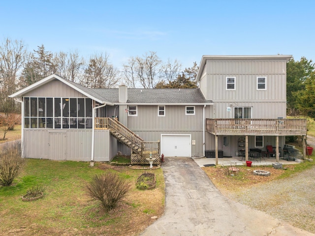 view of front of home with a garage, a front lawn, a patio area, a wooden deck, and a sunroom