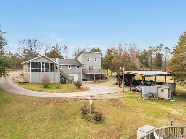 back of house with a sunroom, a lawn, and a carport