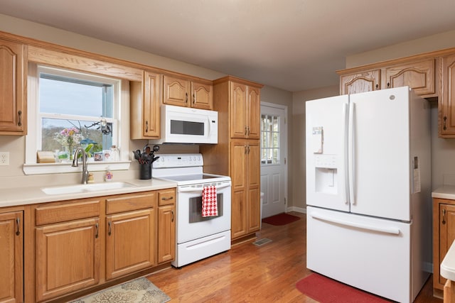 kitchen featuring sink, white appliances, and light wood-type flooring