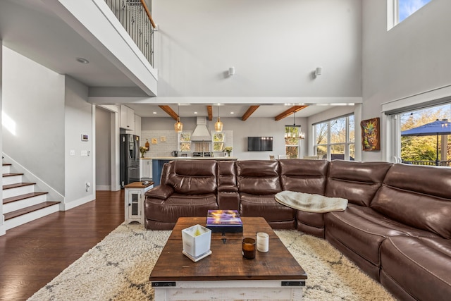 living room featuring dark wood-type flooring, a wealth of natural light, beamed ceiling, and a high ceiling