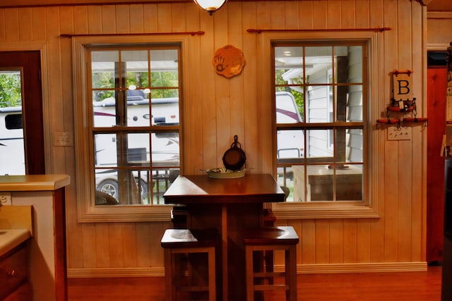 dining area featuring wood-type flooring, a healthy amount of sunlight, and wood walls