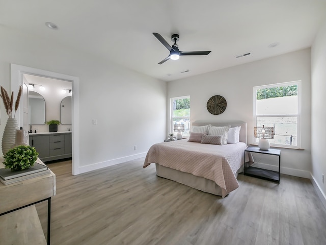 bedroom with ceiling fan, ensuite bath, and light hardwood / wood-style flooring