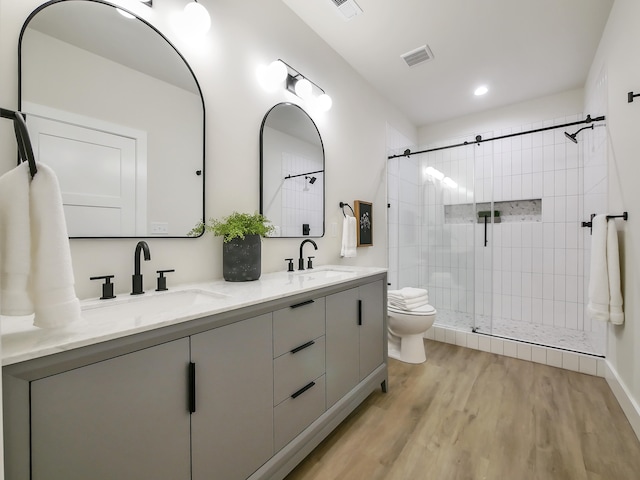 bathroom featuring vanity, toilet, hardwood / wood-style floors, and a tile shower