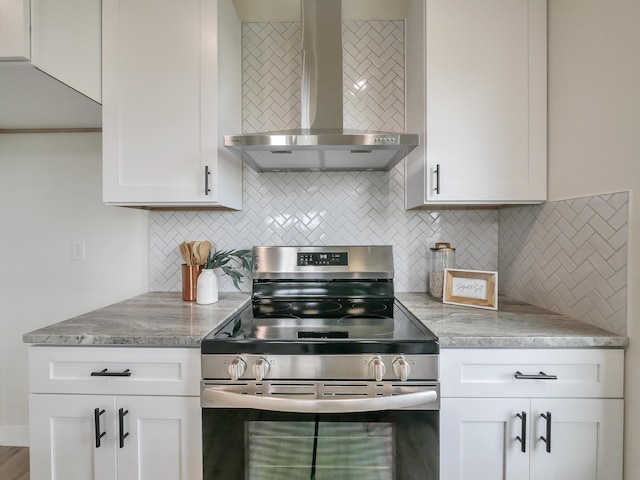 kitchen featuring white cabinetry, tasteful backsplash, light stone counters, electric range, and wall chimney range hood