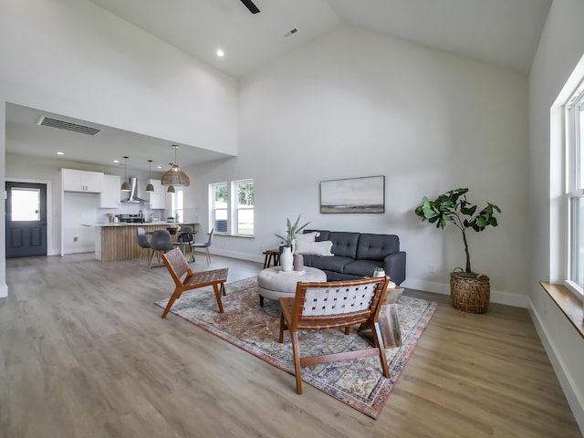 living room with ceiling fan, high vaulted ceiling, and light hardwood / wood-style floors