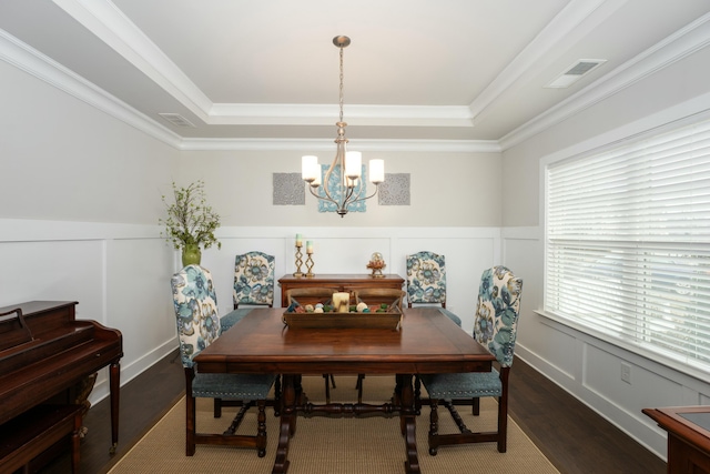 dining room featuring crown molding, a notable chandelier, a tray ceiling, and hardwood / wood-style flooring