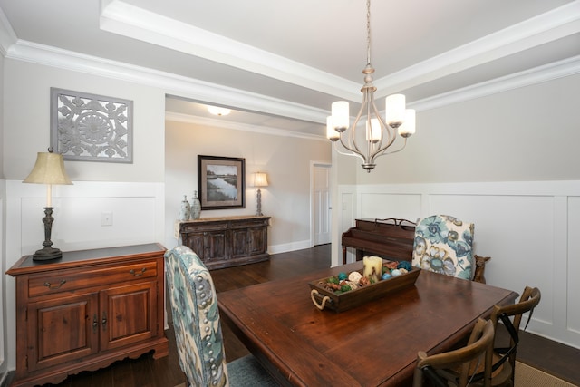 dining space featuring ornamental molding, dark wood-type flooring, an inviting chandelier, and a tray ceiling