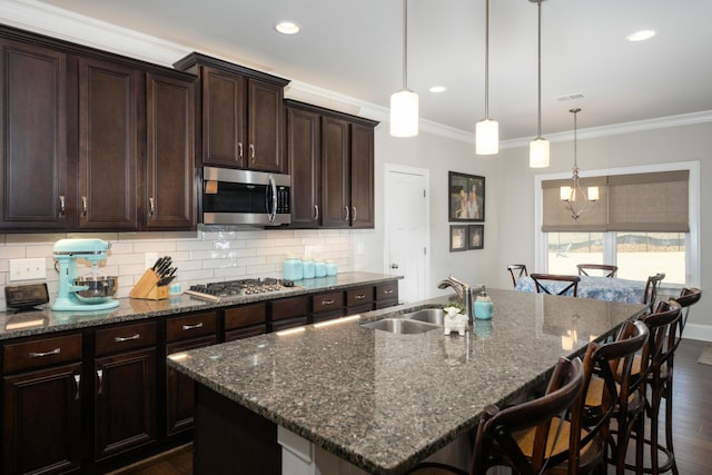 kitchen featuring appliances with stainless steel finishes, sink, a center island with sink, and dark stone counters