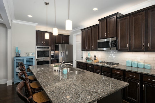 kitchen with an island with sink, appliances with stainless steel finishes, sink, and dark brown cabinetry