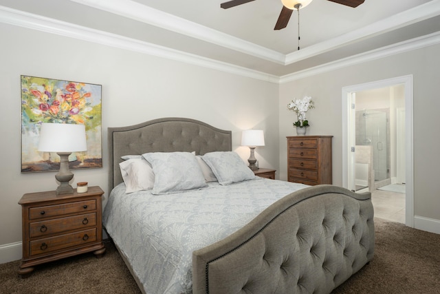 bedroom with crown molding, ceiling fan, ensuite bathroom, dark colored carpet, and a tray ceiling