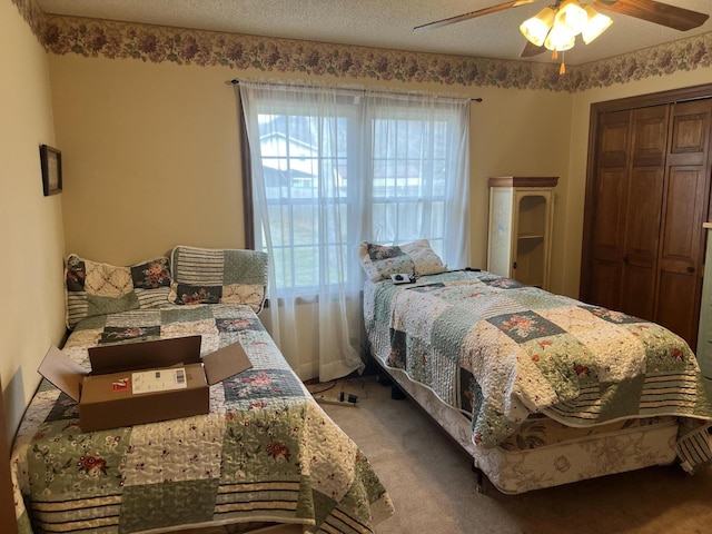carpeted bedroom featuring a closet, ceiling fan, and a textured ceiling