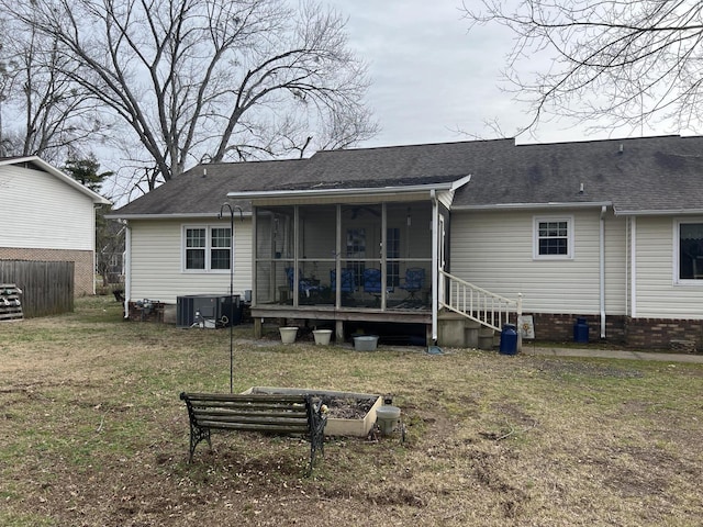 rear view of house with a yard, central AC unit, and a sunroom